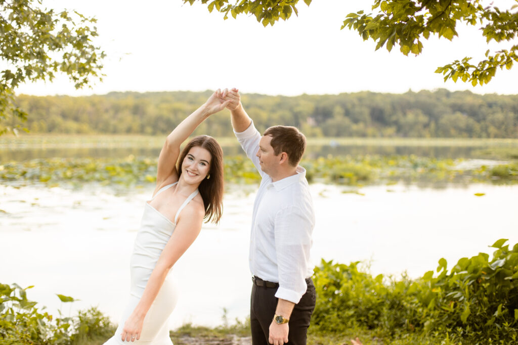 Engaged man spins his fiance around in front of the Lake at Lake Springfield